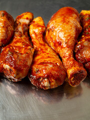 Raw chicken drumsticks on a metal tray. Poultry product for barbeque. Summer season food.