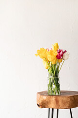 minimal home interior with stylish wooden coffee table and bouquet of fresh tulips
