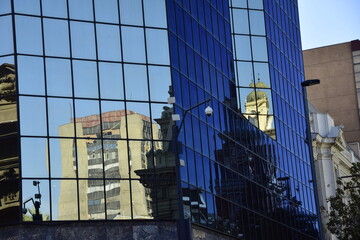 Fototapeta na wymiar The buildings are reflected in the mirrored facade of a modern skyscraper. Santiago. Chile