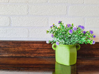 Vase with beautiful purple bouquets on blurred brick wall background