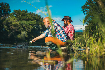 Father and mature son fisherman fishing with a fishing rod on river.