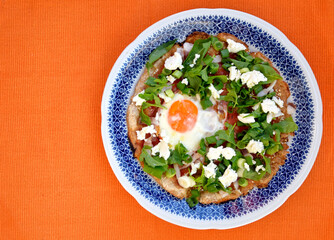 Homemade pizza, top view. Rounded pizza with egg and green vegetables
