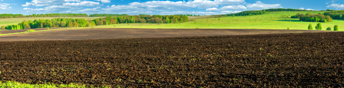 Panorama photo rows of soil before planting. Furrows row pattern in a plowed field prepared for planting crops in spring. Panorama view