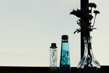 窓際に置かれた花瓶に入れられた造花とハーバリウムフレグランス