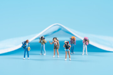Miniature people travel with face mask on blue background,safety travels