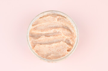 Natural scrub in container on pastel pink background. Homemade cosmetic for spa