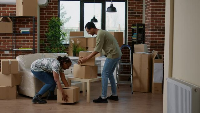 African american couple buying new apartment property, moving in to start family and life together. Married homeowners unpacking cardboard packages for new beginnings on house mortgage.