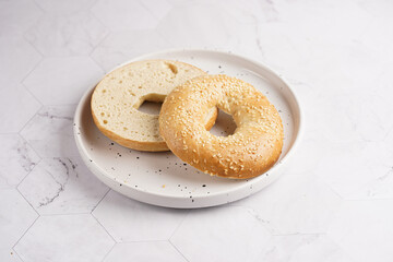 An empty bagel cut in half on white dotted plate on marble background. preparing a sandwich