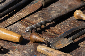 Antique artisan carpenter's tools on a wooden board, selective approach.