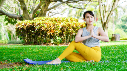 asian girl practicing yoga in park, beautiful woman sitting on mat for morning relaxing yoga pose , exercise in park, mental health care, health and sports