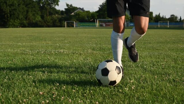 Soccer player is training outdoors on the field at summer daytime