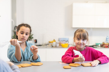 Obraz na płótnie Canvas two cute sisters make and decorate cookies