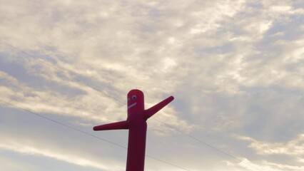 Air moving man - street advertising, Inflatable red dancer figure moving against cloudy sky