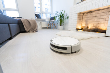 Robotic vacuum cleaner on laminate wood floor in bedroom.