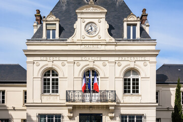 Facade of a french city hall with national motto of France "Liberty, Equality, Fraternity" engraved and flags.