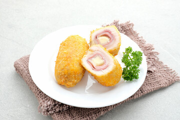 Crispy Cordon Blue, Chicken fillet roll with ham and cheese. Served in white plate on grey background. 
