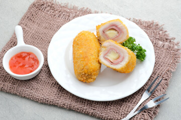 Crispy Cordon Blue, Chicken fillet roll with ham and cheese. Served in white plate on grey background. 
