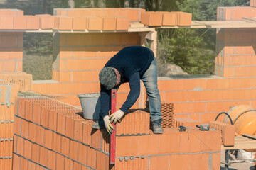 The builder will check the level of the vertical wall of the house being built. Bricklaying....