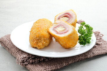 Crispy Cordon Blue, Chicken fillet roll with ham and cheese. Served in white plate on grey background. 
