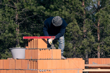 The builder will check the level of the horizontal wall of the house being built. Bricklaying....