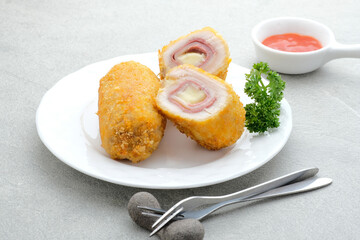 Crispy Cordon Blue, Chicken fillet roll with ham and cheese. Served in white plate on grey background. 
