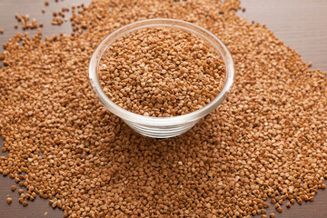 Buckwheat in a bowl in a wooden bowl with bagged in the background.