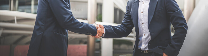 Two businessman shaking hands with business deals and congratulations on success. Image panorama...