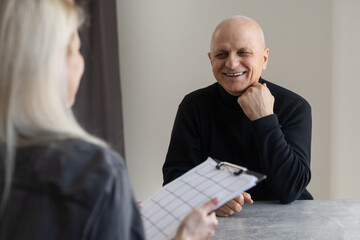 Portrait of female psychiatrist interviewing senior man during therapy session, copy space