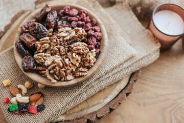 Nuts, dates and cranberries in a wooden plate, top view