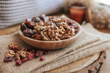 Nuts, dates and cranberries in a wooden plate, top view
