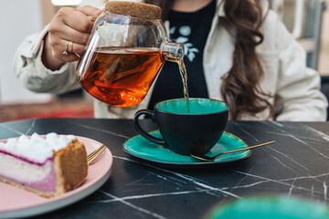 Girl in a cafe pours tea