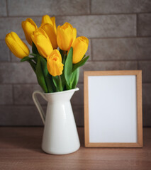 Beautiful tulip flowers  and blank picture frame on table at kitchen