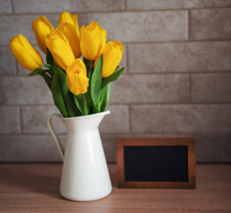 Beautiful yellow tulip flowers  and blank blackboard picture frame on table