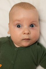 close-up portrait of a three-month-old baby with blue eyes dressed in green