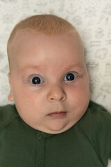 close-up portrait of a three-month-old baby with blue eyes dressed in green