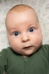 close-up portrait of a three-month-old baby with blue eyes dressed in green