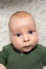 close-up portrait of a three-month-old baby with blue eyes dressed in green