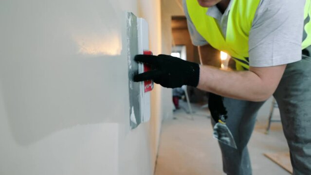Repair work in the room. Construction worker applies putty to the wall close-up.