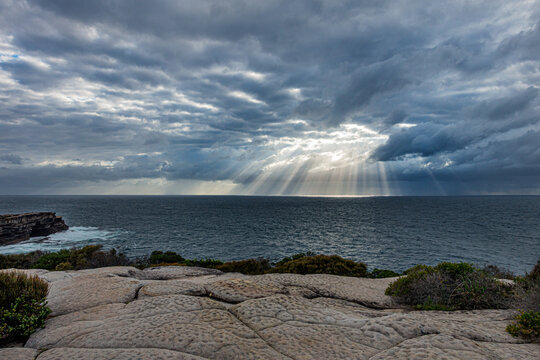 Bright morning sunlight shining through hole in the clouds over the sea at Maroubra Beach, Randwick, Sydney, Australia.