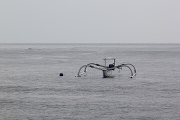 Sea landscape with storm - indonesian traditional fishing boat float in grey ocean with drip drops...