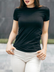 Stylish brunette girl wearing black t-shirt posing against street , urban clothing style. Street...