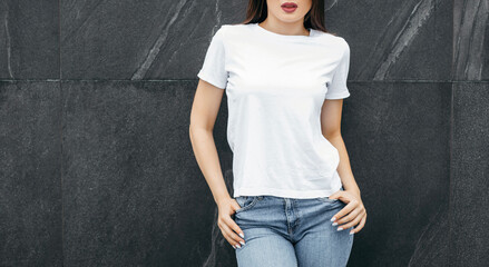 Stylish brunette girl wearing white t-shirt posing against street , urban clothing style. Street...