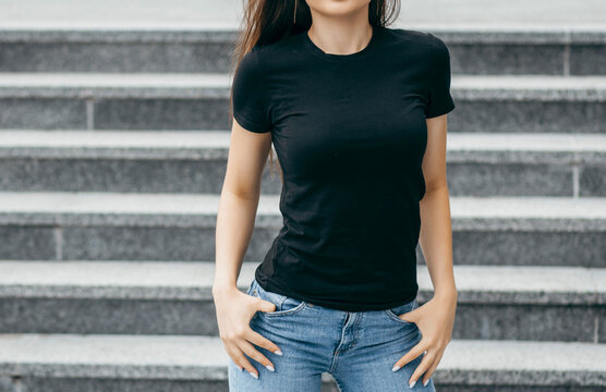 Stylish brunette girl wearing black t-shirt posing against street , urban clothing style. Street photography	
