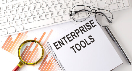 ENTERPRISE TOOLS text written on a notebook with keyboard, chart,and glasses