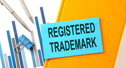Registered trademark text on sticker on the yellow notebook with chart and pen