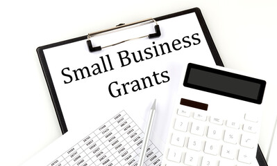 SMALL BUSINESS GRANTS text on folder with chart and calculator on white background