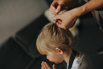 Mom makes a ponytail for a little daughter.