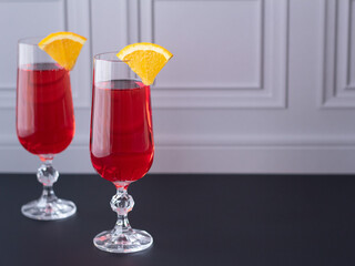 Red alcoholic beverage. Campari coctail decorated with pieces of orange. Party drinks.