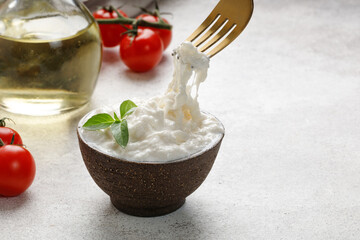 Stracciatella cheese on grey background with fork, oil, basil and tomatoes. Curd cheese product. - obrazy, fototapety, plakaty