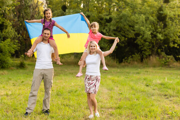 Obraz premium Flag Ukraine in hands of little girl in field. Child carries fluttering blue and yellow flag of Ukraine against background field.